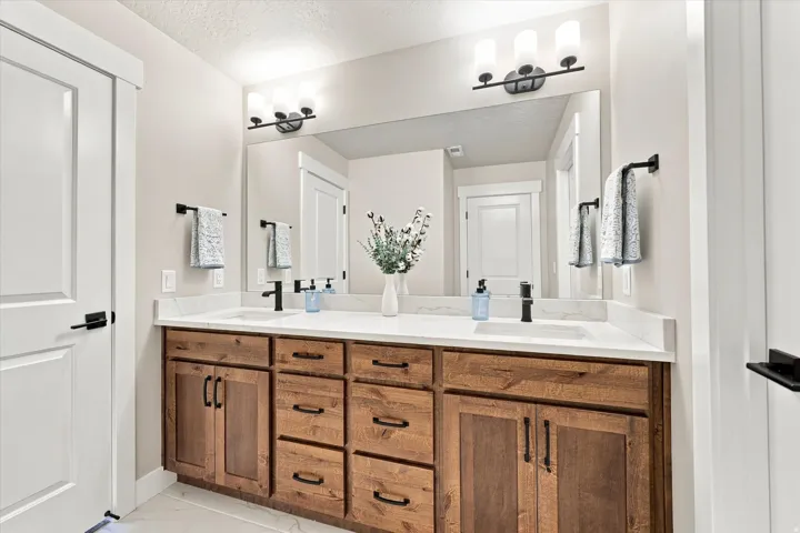 Dual vanity with wood-finish cabinetry and white countertops.