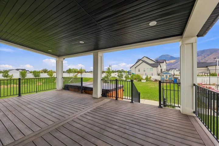 Large covered deck with recessed lighting, composite decking, and black metal railings.