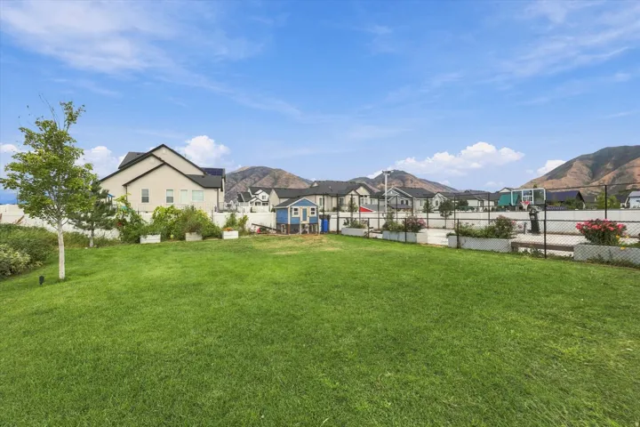 Expansive green lawn, raised planter beds, a basketball court, and mature landscaping with fruit trees.