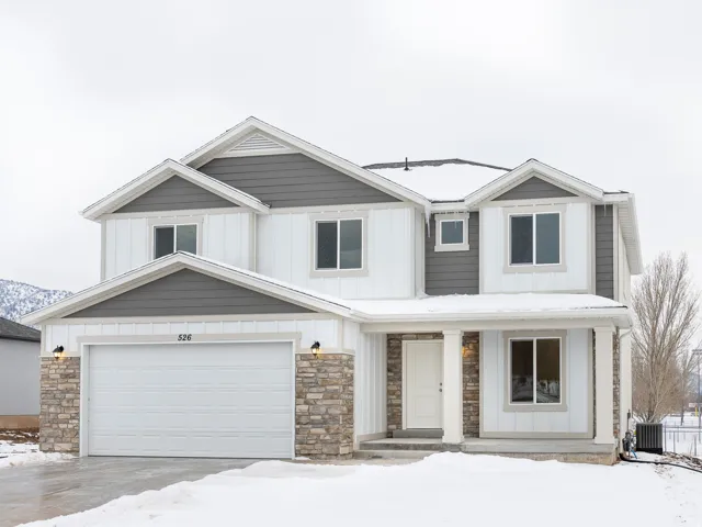 Two-story residence featuring a covered entry, stone veneer accents, and a two-car garage