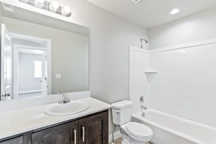 Single vanity with wood-finish cabinetry, white countertop, and integrated sink