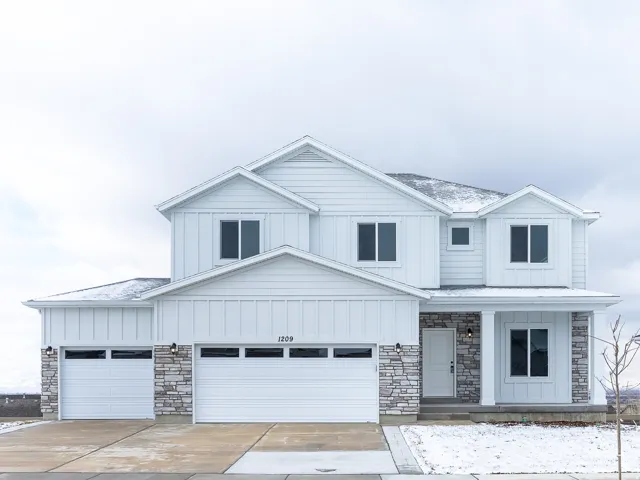 Two-story property featuring white horizontal siding, a stone veneer facade, a covered entry porch with columns, a two-car garage, and a single-car garage
