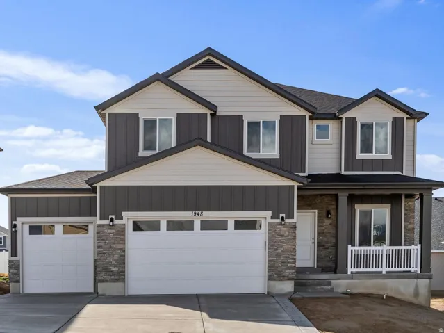 Two-story residence featuring a covered entry, stone column accents, and a two-car garage