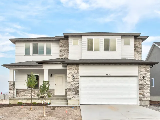 Two-story residence featuring light-colored horizontal siding and stacked stone accents
