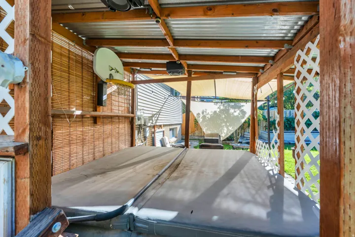 Covered outdoor structure featuring wood beams, a corrugated metal roof, and lattice detailing