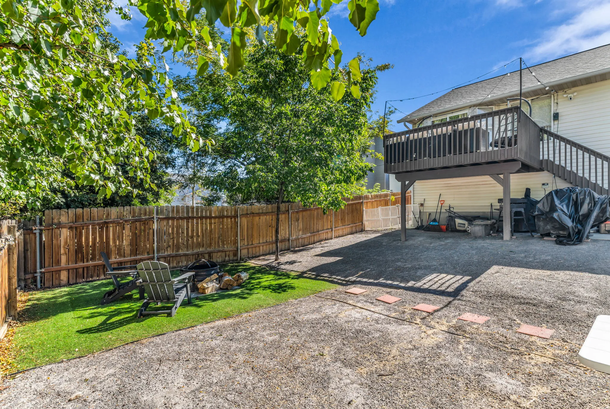 Expansive outdoor area featuring a wood fence, gravel patio, artificial turf, and a raised wood deck