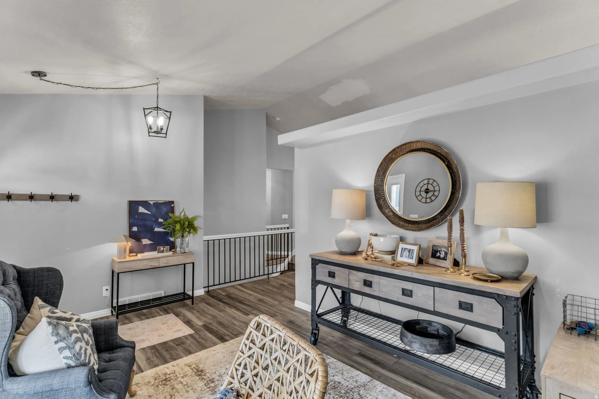 Vaulted ceiling with a suspended light fixture, wood-finish flooring, and a metal railing