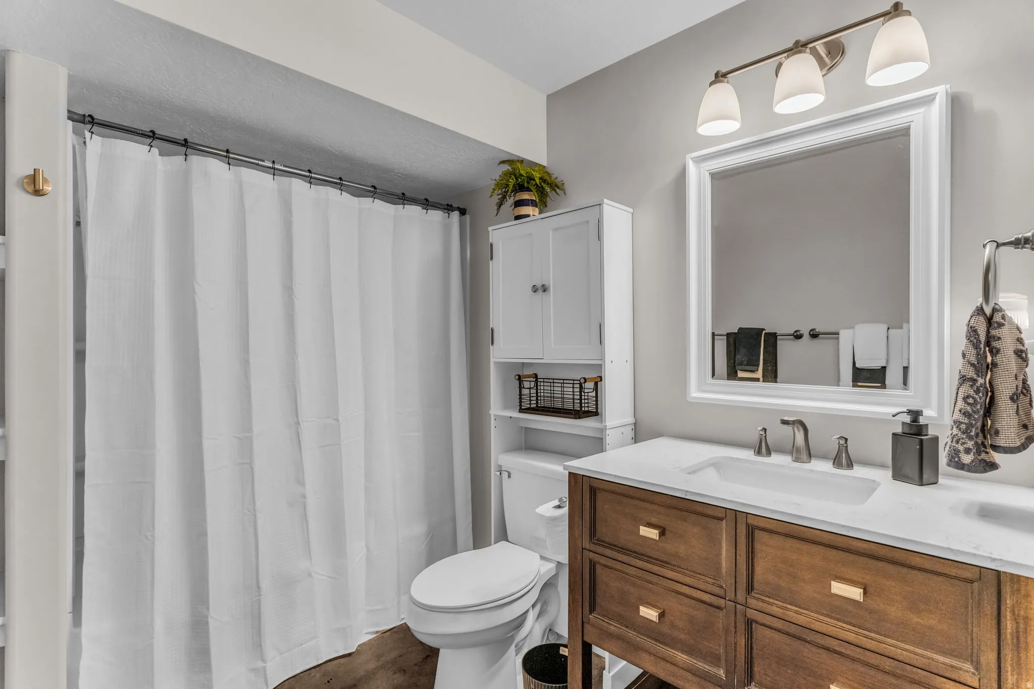 Wood-finish flooring with a white toilet and shower area