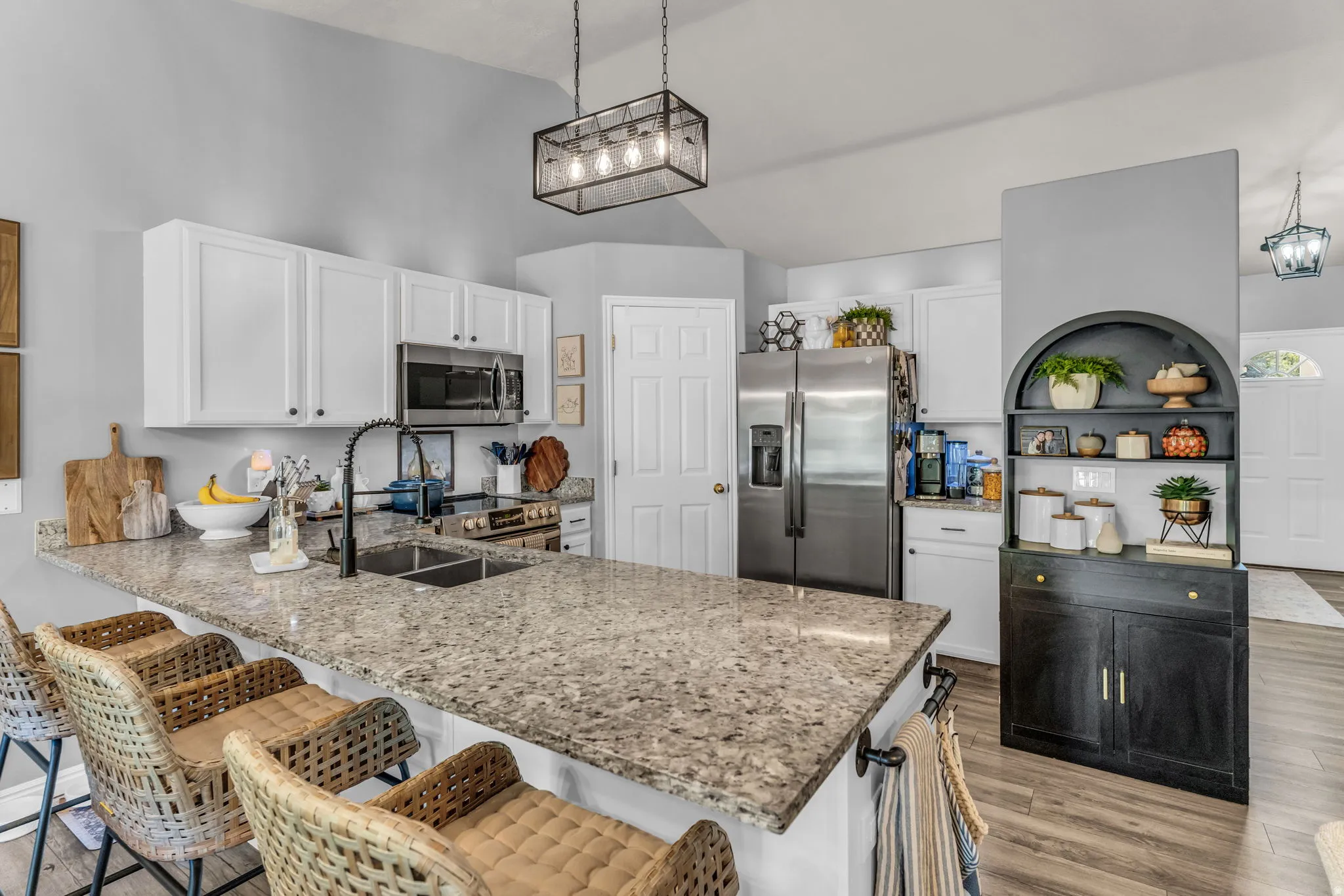 Kitchen featuring an expansive island with a dual basin sink, white cabinetry, stainless steel appliances, and wood-finish flooring