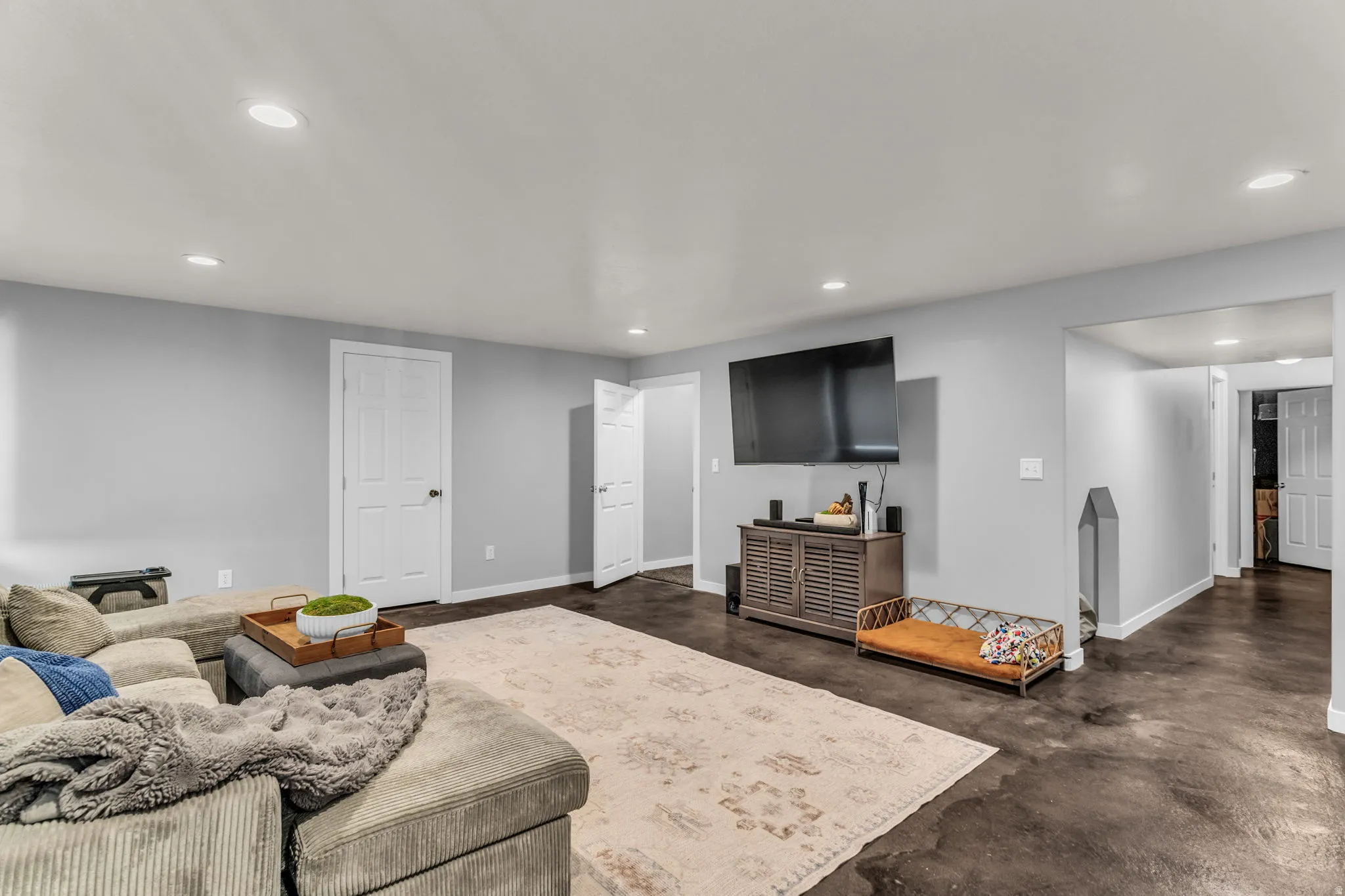 Recessed ceiling lighting, light gray wall paint, dark concrete-finish flooring, and white interior doors