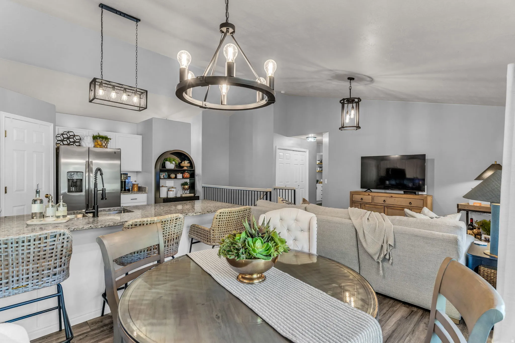 Open concept living area featuring a kitchen island with granite countertops, stainless steel appliances, wood-finish flooring, a contemporary chandelier, and recessed lighting