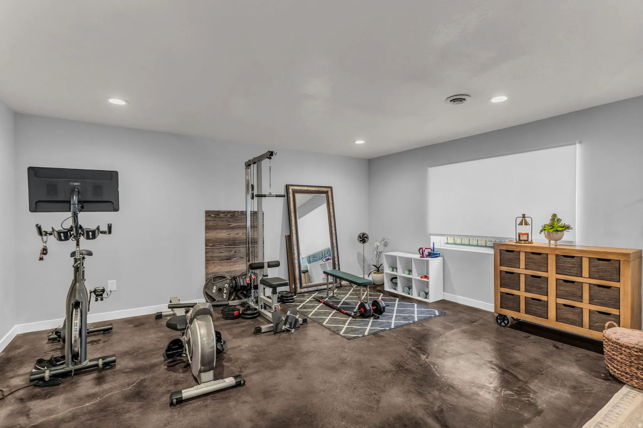 Recessed lighting illuminates the room, featuring light gray walls and dark, textured flooring
