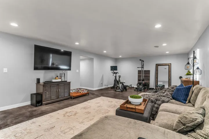 Recessed ceiling lighting, durable dark flooring, and a media console with slatted doors