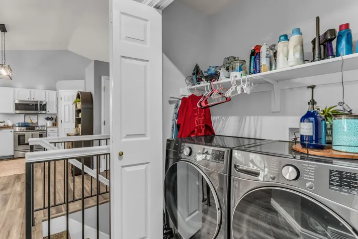 Dedicated laundry area with built-in shelving, wood-finish flooring, and a railing with metal spindles