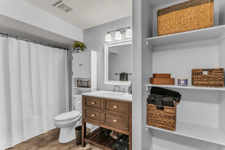 Wood-finish flooring, white vanity with integrated sink, white built-in storage cabinet, and open shelving