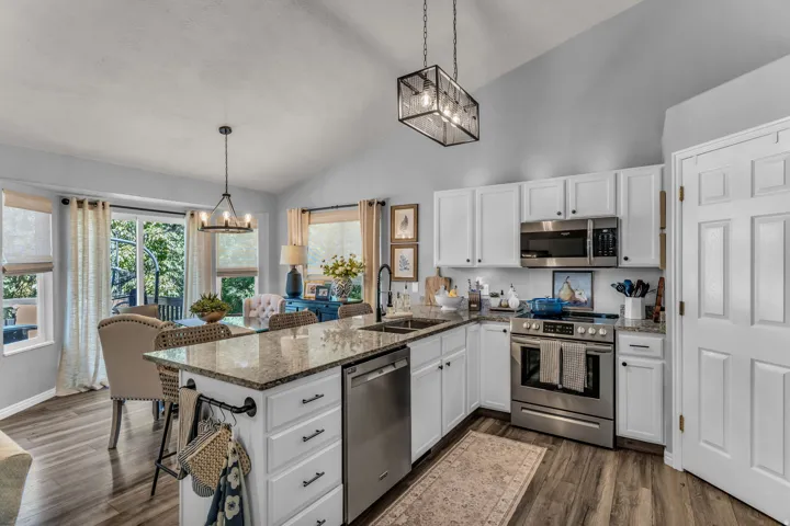 Kitchen featuring white cabinetry, stainless steel appliances, granite countertops, and wood-finish flooring