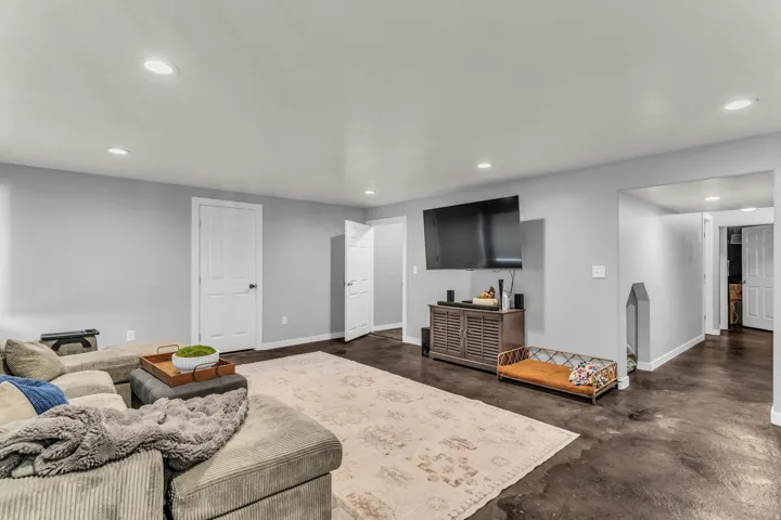 Recessed ceiling lighting, light gray wall paint, dark concrete-finish flooring, and white interior doors