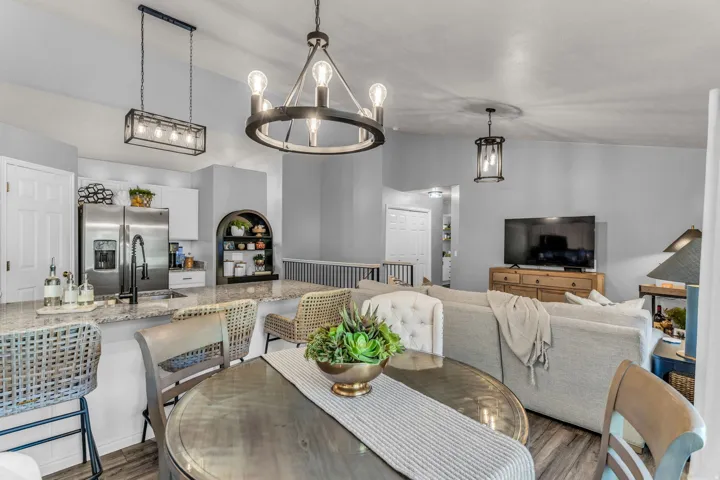 Open concept living area featuring a kitchen island with granite countertops, stainless steel appliances, wood-finish flooring, a contemporary chandelier, and recessed lighting
