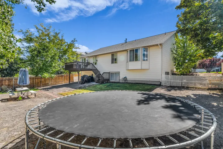 Rear exterior with a wood deck, outdoor stairs, white horizontal siding, and multiple windows