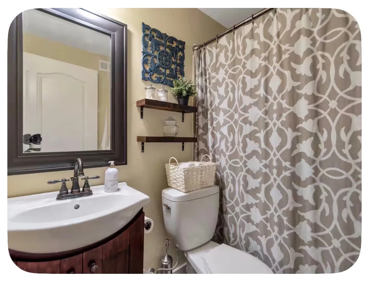 Bathroom featuring a wood-finish vanity with a white ceramic sink, a framed mirror, and wall-mounted shelving