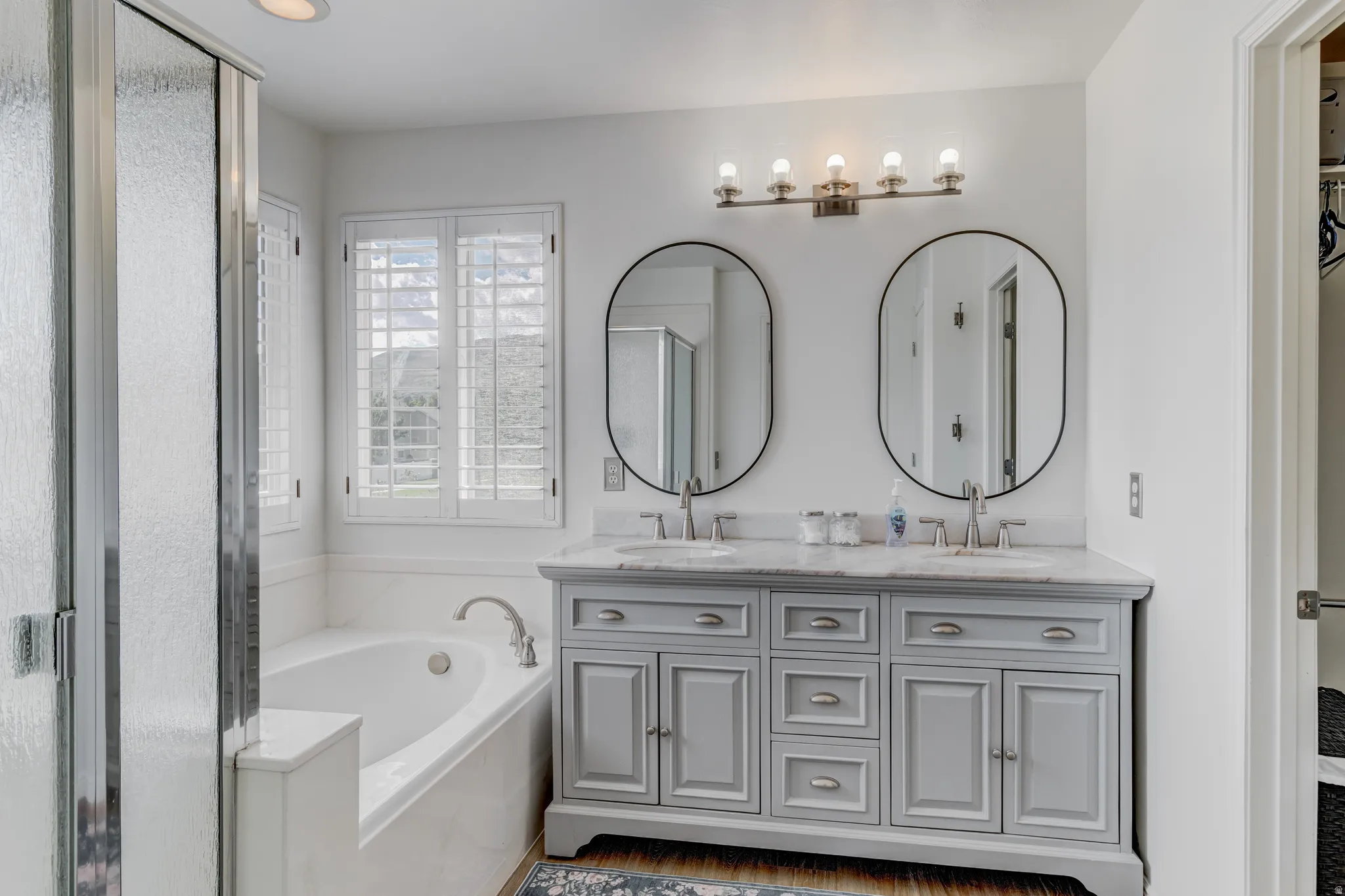 Dual vanity with an integrated countertop, oval mirrors, and brushed nickel fixtures