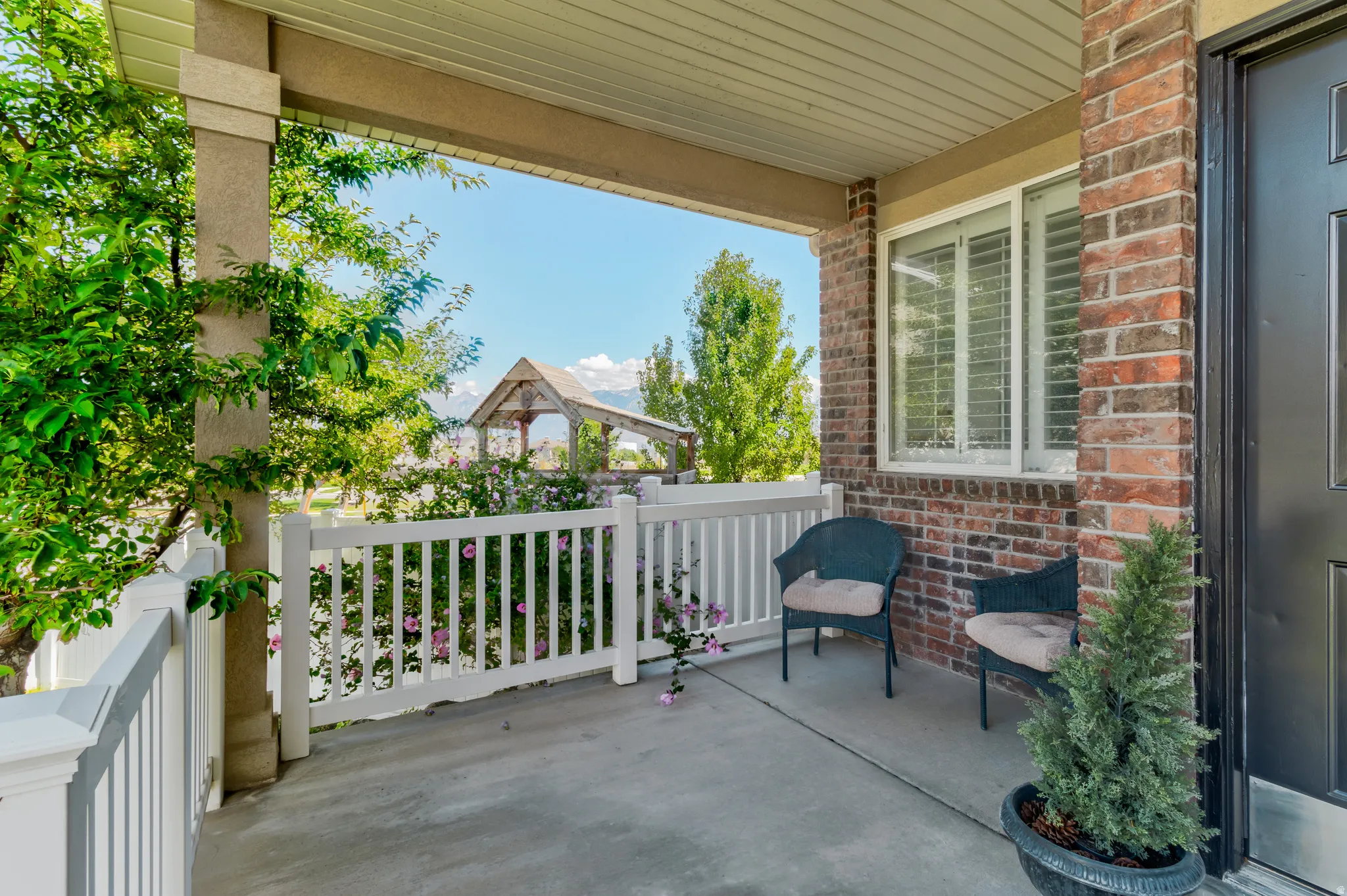 Covered porch featuring a brick facade, white railing, and concrete flooring