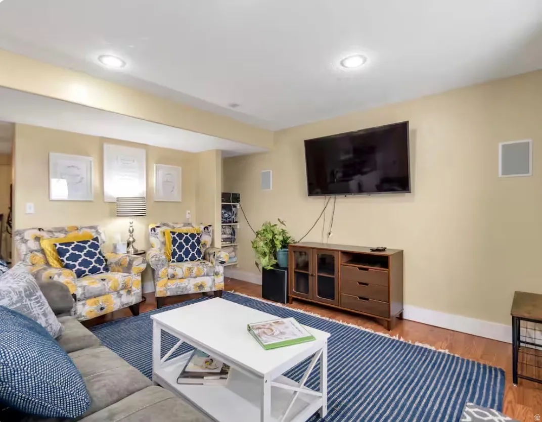 Recessed ceiling lighting, wood-finish flooring, built-in wall speakers, and a media console