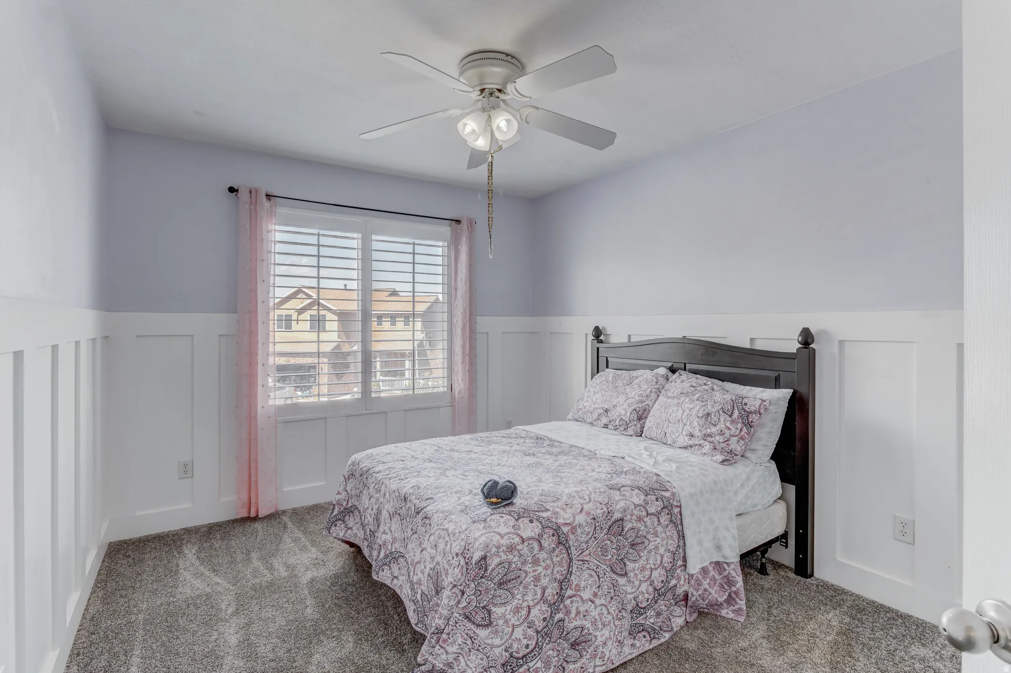 Room featuring board and batten wall detailing, a window with louvered shutters, ceiling fan with integrated lighting, and carpeted flooring