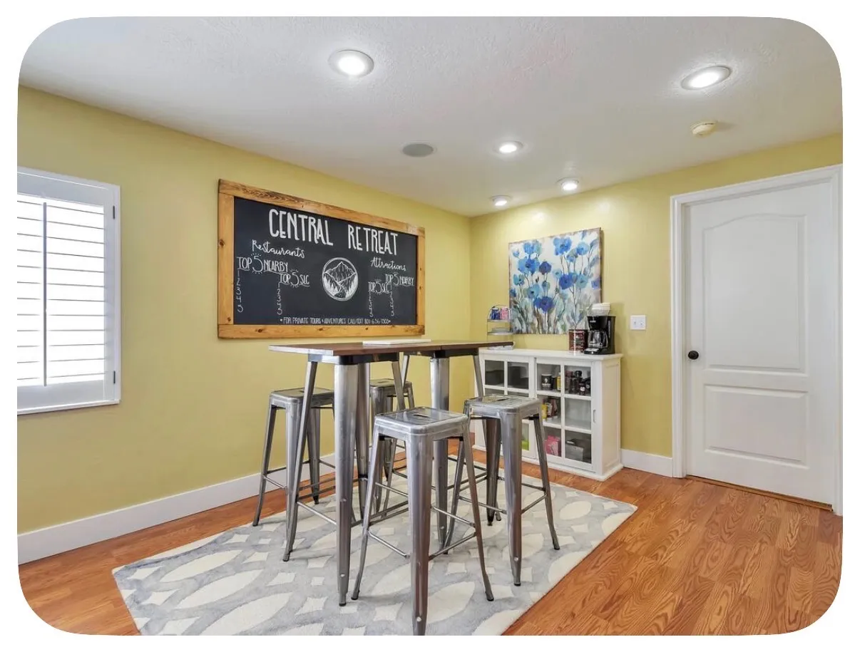 Recessed lighting, wood-finish flooring, white plantation shutters, white interior door with black hardware, and a built-in white cabinet with glass doors