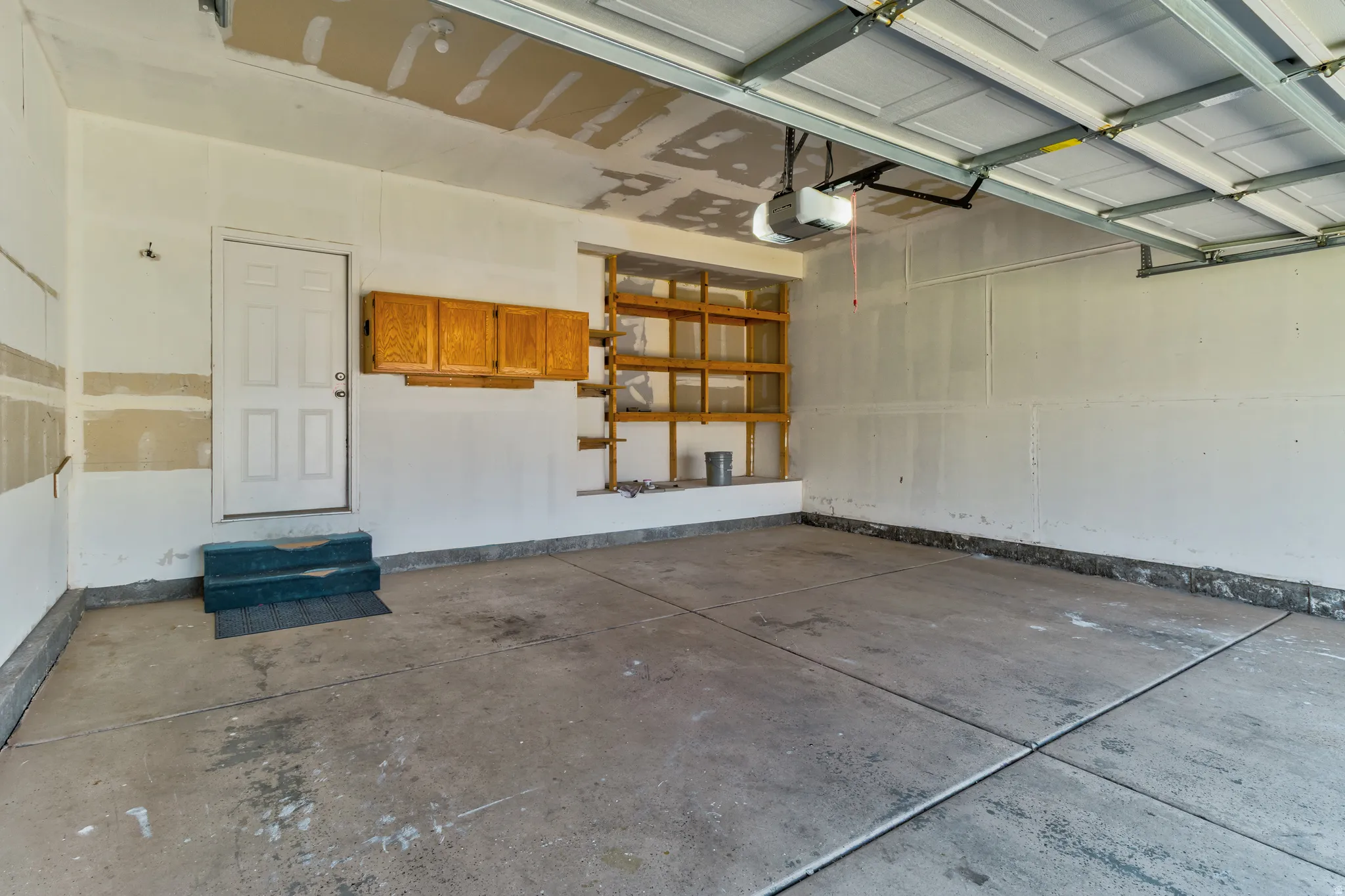 Concrete flooring, built-in shelving, mounted cabinetry, and a garage door opener