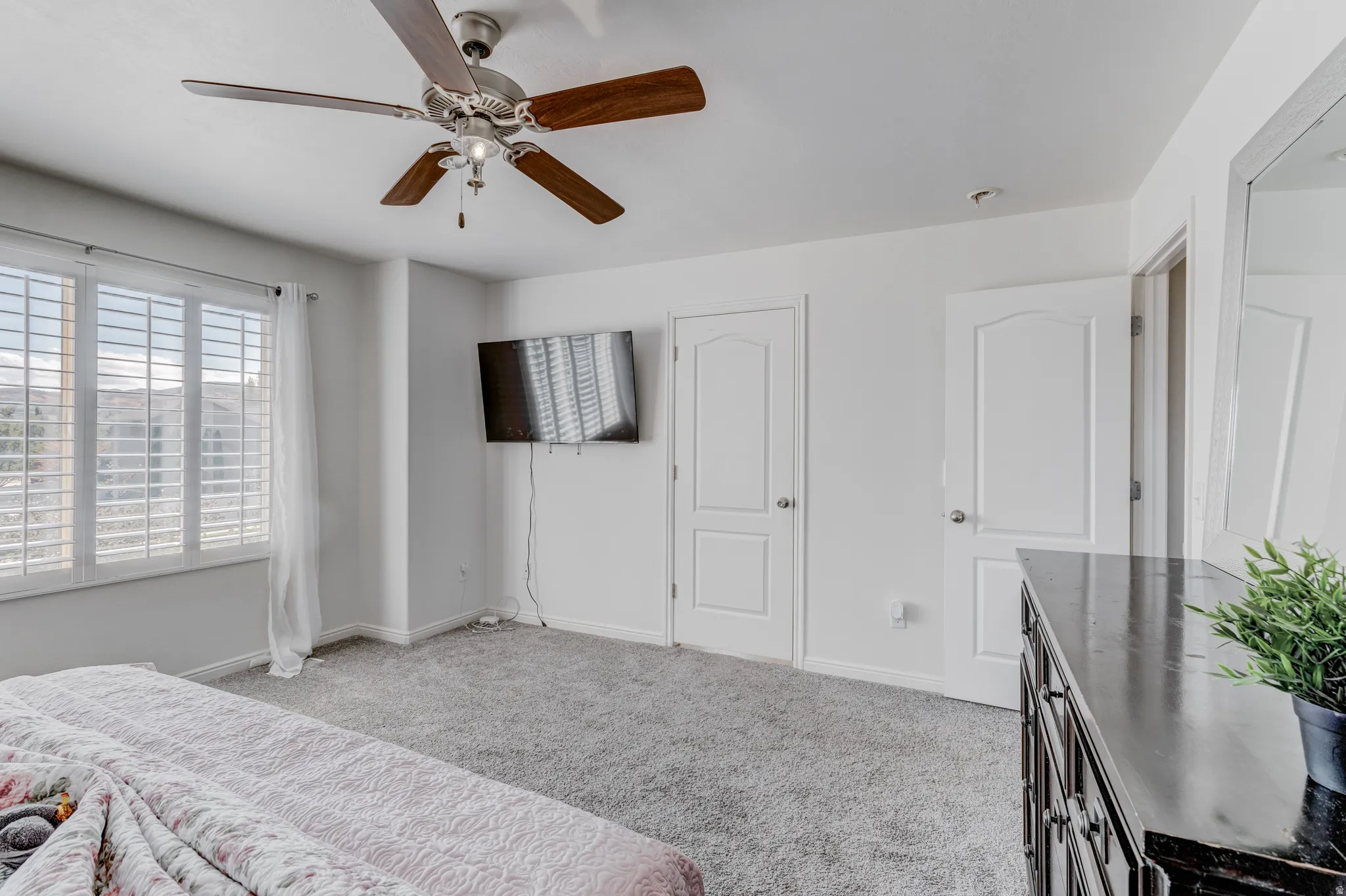 Recessed lighting, ceiling fan with wood-finish blades, white plantation shutters, two paneled doors, and light gray carpeting