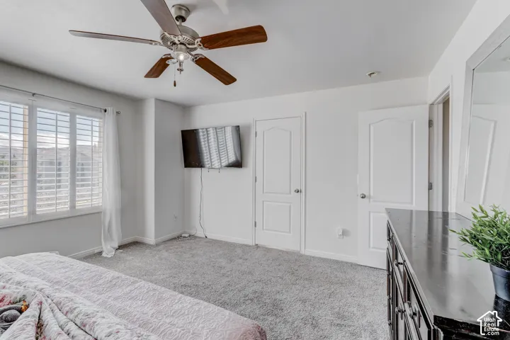 Recessed lighting, ceiling fan with wood-finish blades, white plantation shutters, two paneled doors, and light gray carpeting