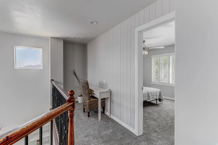 Hardwood railing with wrought iron balusters, recessed lighting, accent wall with vertical paneling, and a transom window