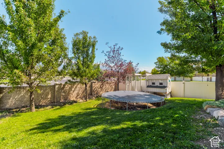 Expansive backyard featuring a manicured lawn, established trees, and a stone retaining wall