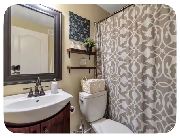 Bathroom featuring a wood-finish vanity with a white ceramic sink, a framed mirror, and wall-mounted shelving