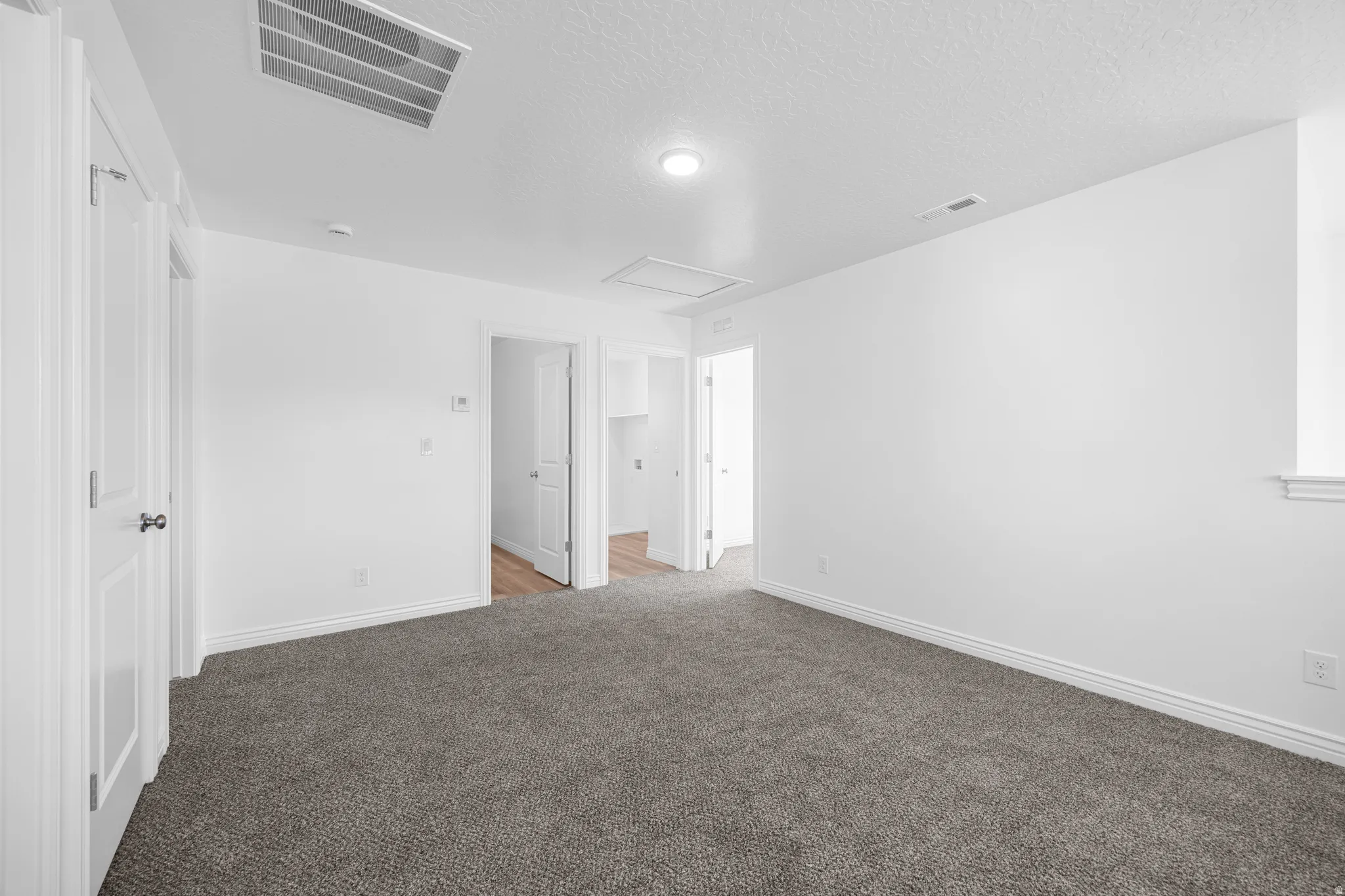 Carpeted flooring, white walls, multiple doorways, and recessed lighting