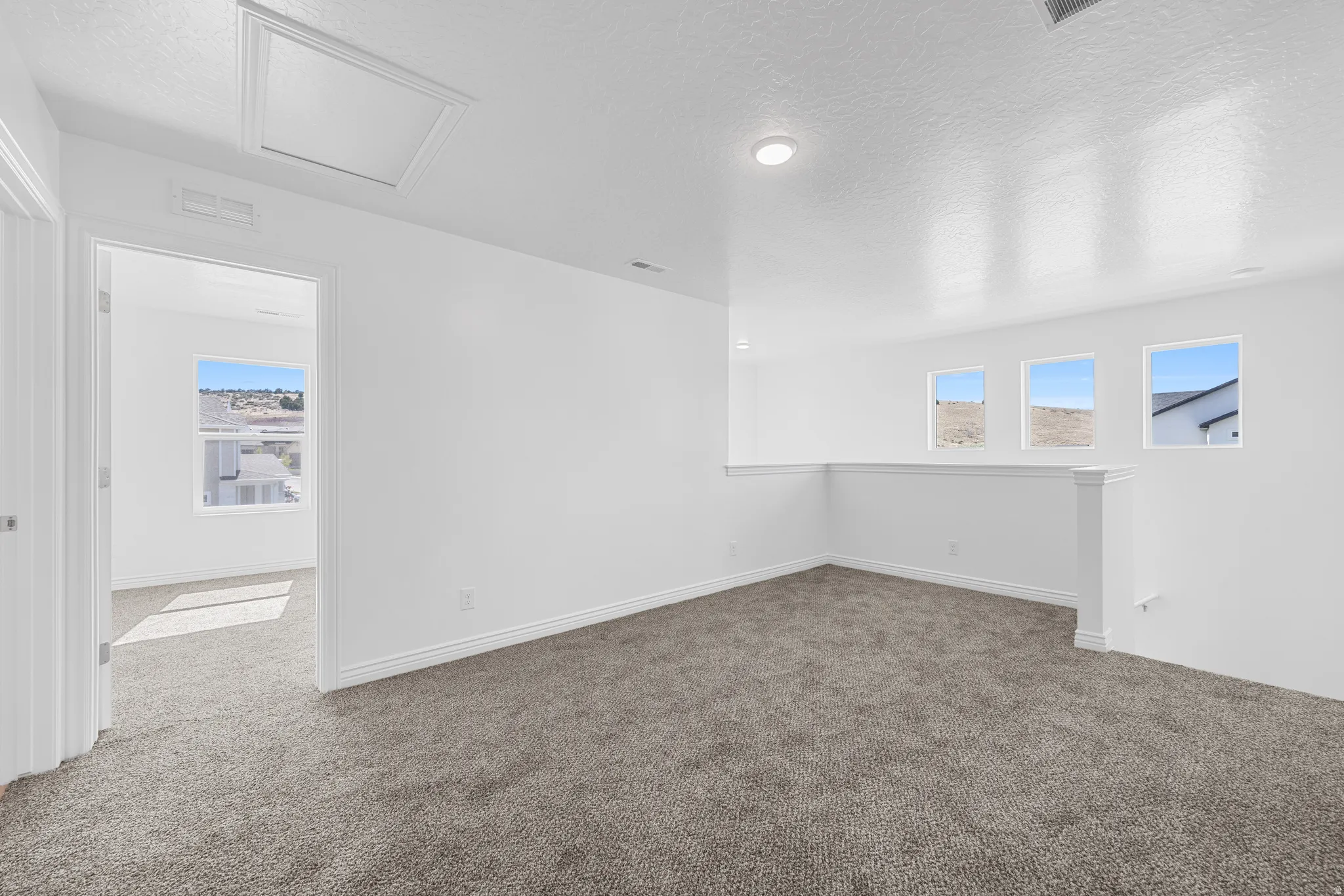 Carpeted loft area featuring three rectangular windows and recessed lighting