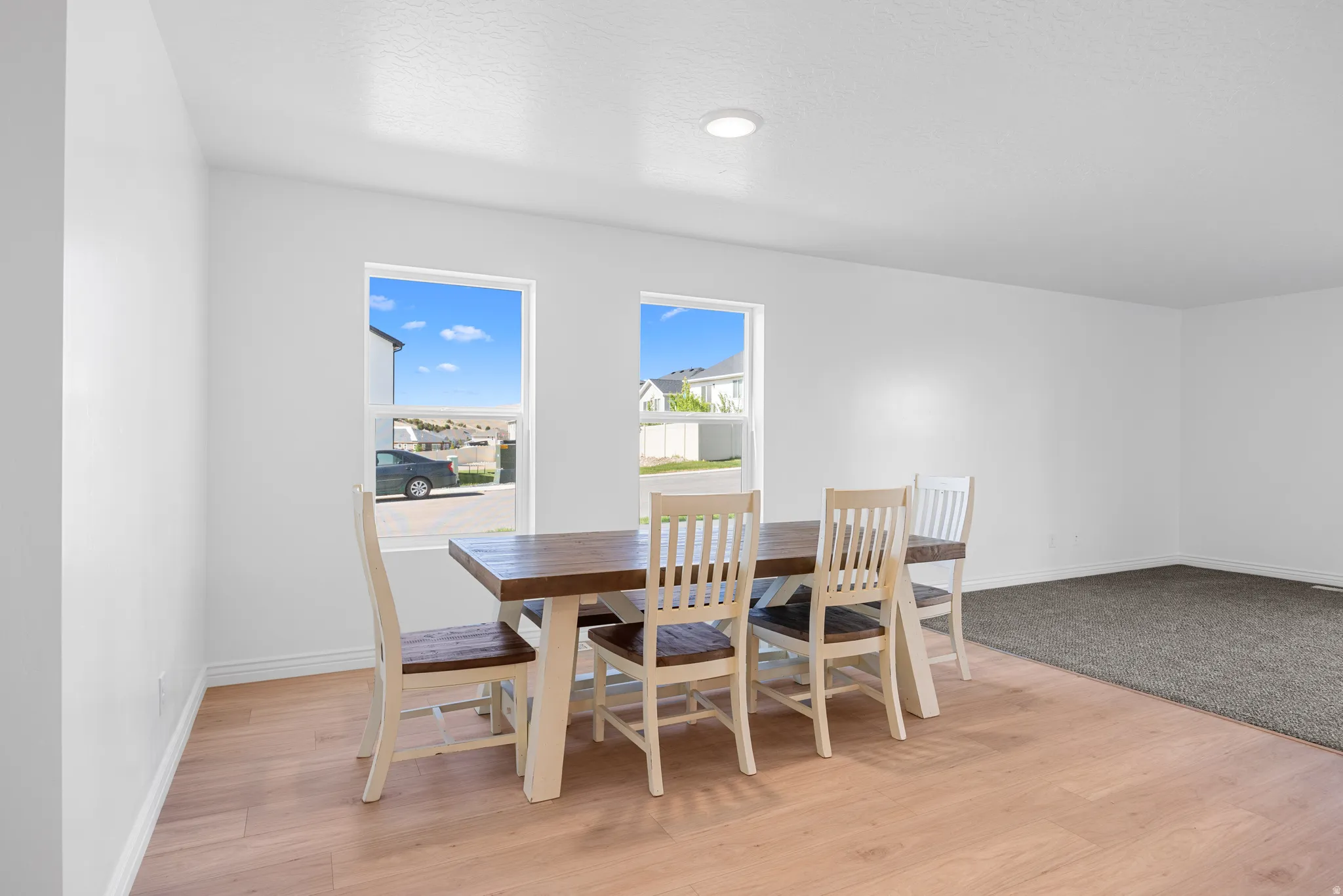 Recessed ceiling lighting, multiple large windows, wood-finish flooring, and a carpeted area