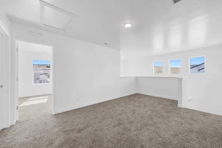 Carpeted loft area featuring three rectangular windows and recessed lighting