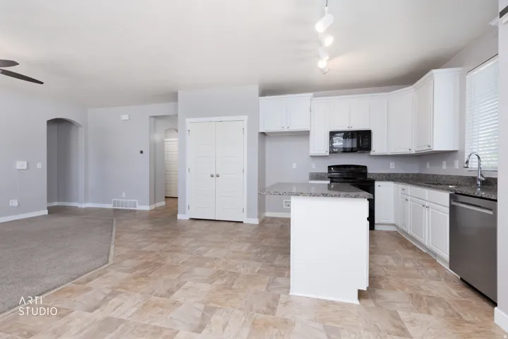 Kitchen with white cabinetry, granite countertops, and stainless steel dishwasher