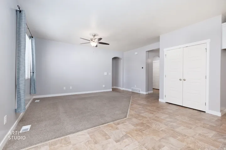 Vaulted ceiling with a ceiling fan, light gray wall paint, and light tan tile-patterned flooring