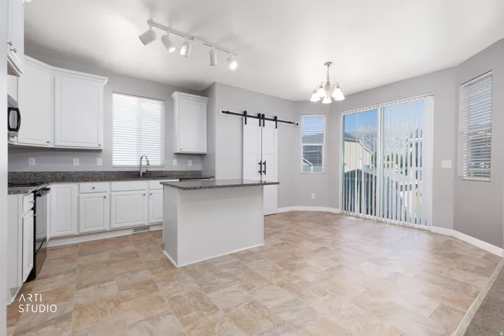 White cabinetry with dark countertops, a kitchen island, track lighting, and sliding glass doors