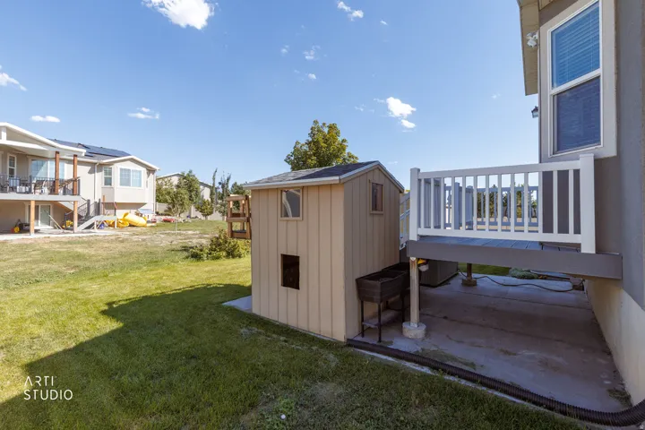 Elevated deck with white railing, concrete patio, and a detached shed