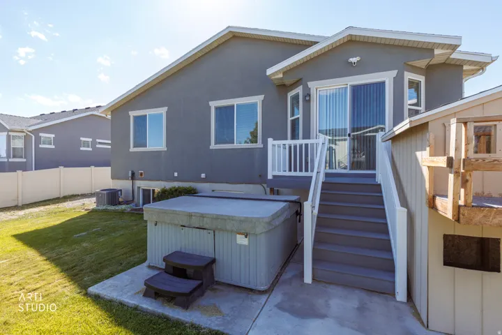 Rear exterior with a concrete patio, built-in hot tub, and direct access to an upper-level deck