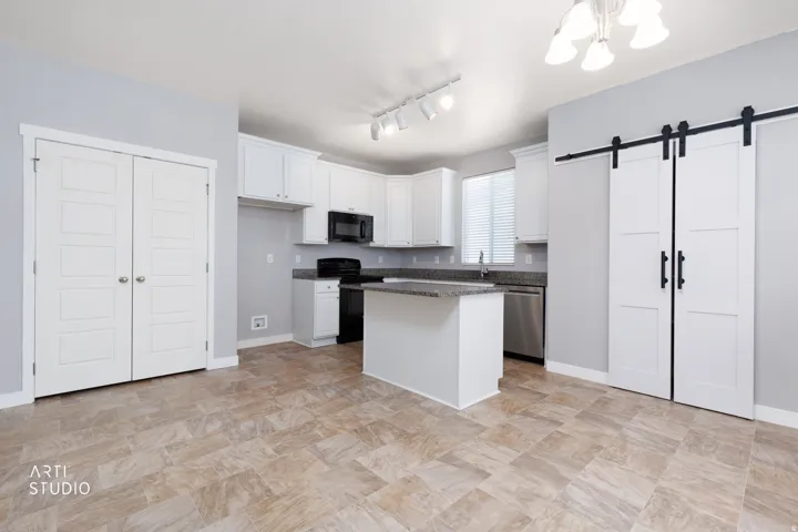 Kitchen featuring white cabinetry, a center island, dark countertops, black appliances, and tile flooring