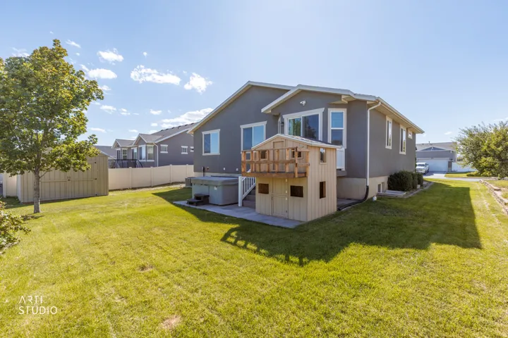 Expansive green lawn with a privacy fence, an exterior storage shed, and a built-in play structure
