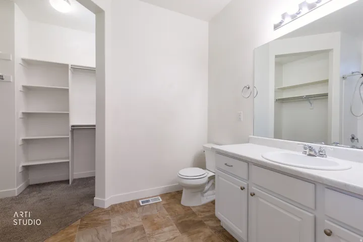 White vanity with a single basin sink, white countertop, and brushed nickel faucet
