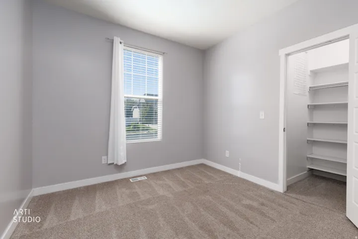 Carpeted flooring, single window with blinds, light gray wall finish, and a closet with built-in shelving