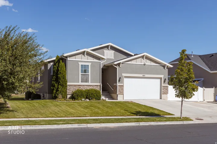 Contemporary stucco exterior with stone accents, a two-car garage, and a manicured front lawn