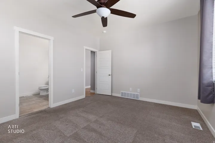 Neutral wall paint, ceiling fan, carpet flooring, flat panel interior doors, and tile flooring visible in the bathroom